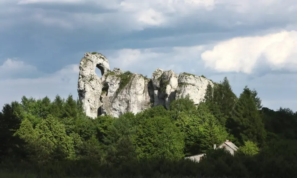 Imponujący okiennik wielki, skalna brama wśród zieleni, z ukrytą chatką.
