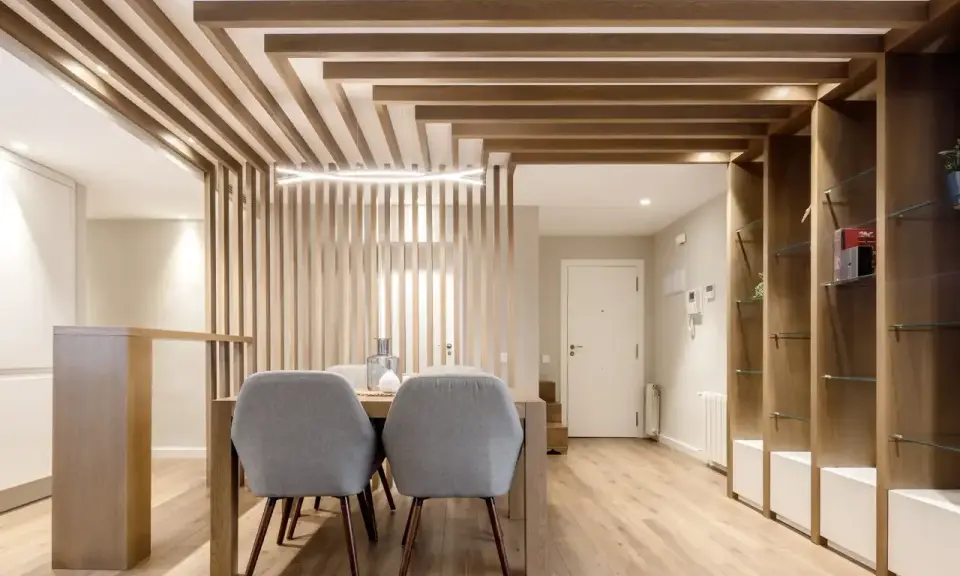 Comedor moderno con separador de listones de madera y estanterías. Preguntarse cuanto se tarda en tirar un tabique es irrelevante aquí.