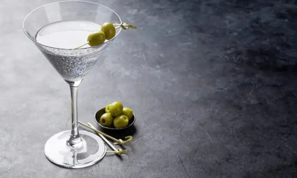 Un verre de dry martini, garni de deux olives, prêt à être dégusté. La recette parfaite pour un apéritif chic.