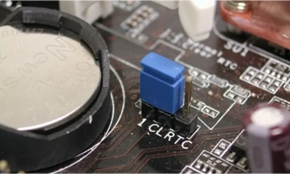 Gros plan sur une carte mère, montrant la pile bouton et le cavalier CLRTC pour réinitialiser le CMOS.