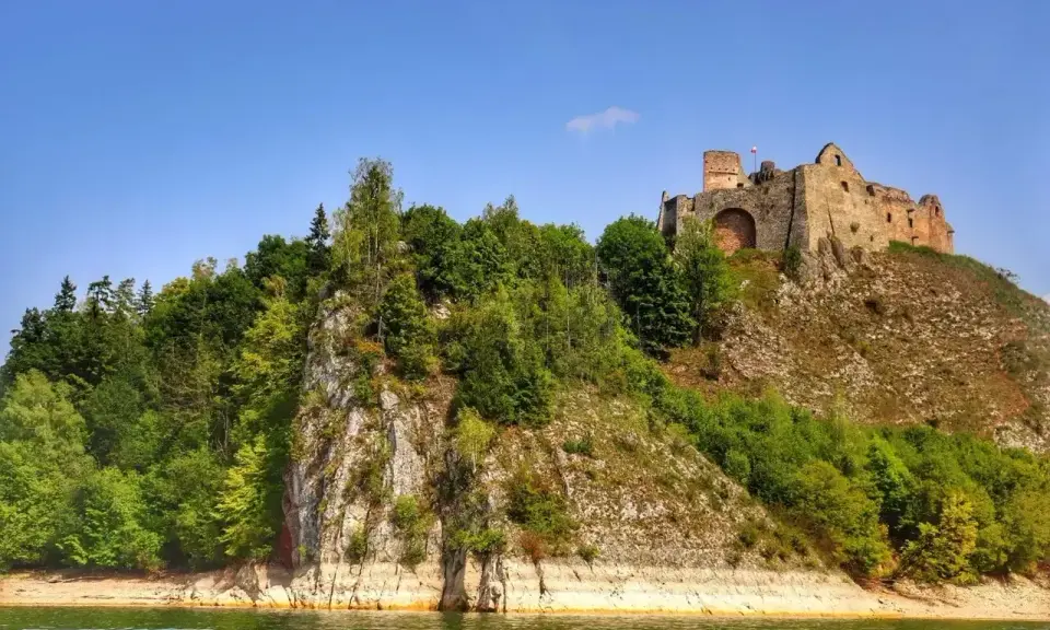Zamek Czorsztyn góruje nad jeziorem, otoczony zielenią. Ruiny zamku na skale, widok z wody.
