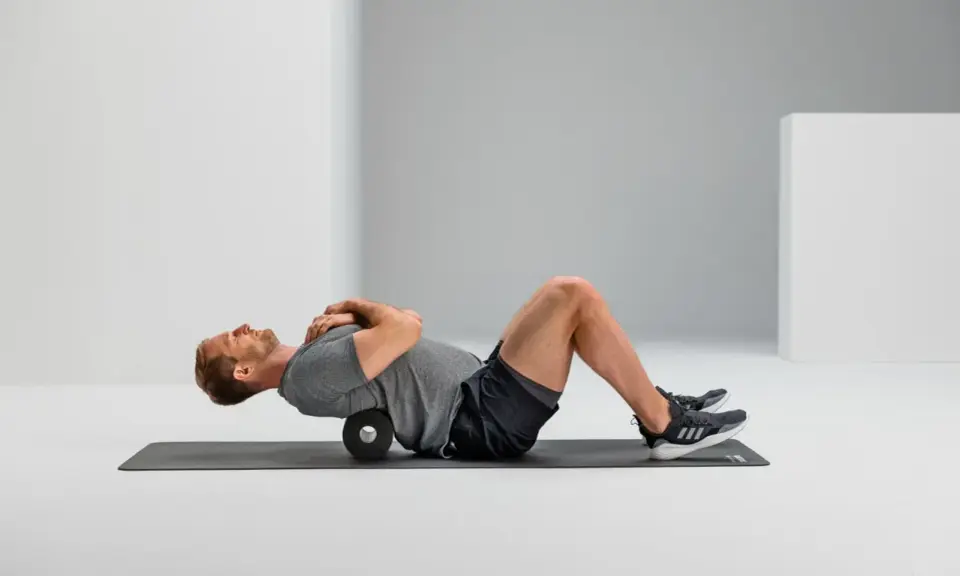 Mann macht Foam Rolling auf einer Matte, um seinen Rücken zu entspannen.