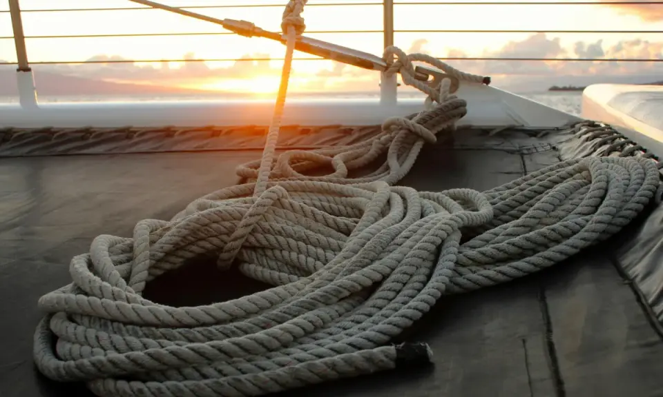Coup de soleil sur un bateau, une corde épaisse est prête à faire un noeud de marin.