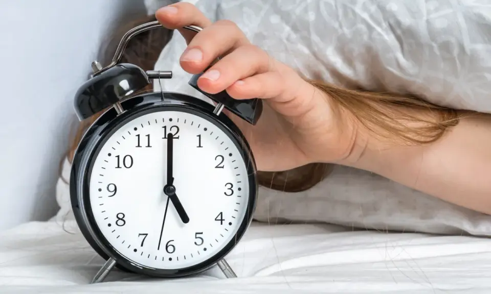 Ręka wyłącza budzik. Jest 5:00, a 0303 znaczenie tego czasu to nowy początek dnia.