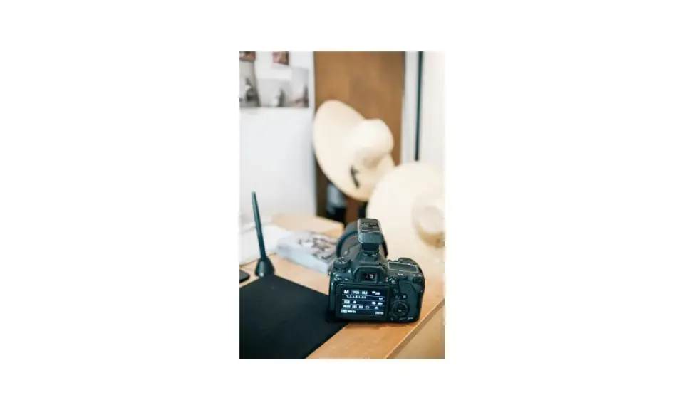 Aparat fotograficzny na biurku, obok kapelusze i tablet graficzny. To miejsce, gdzie zaczyna się nauka, jak zarabiać na zdjęciach.