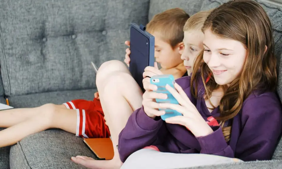 Trois enfants absorbés par leurs écrans, un rappel pour un atelier sensibilisation aux écrans.
