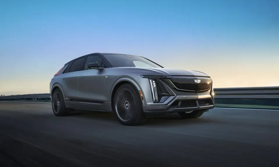 Cadillac Lyriq, un SUV eléctrico que representa el futuro de las marcas americanas de coches, avanza por una carretera al atardecer.