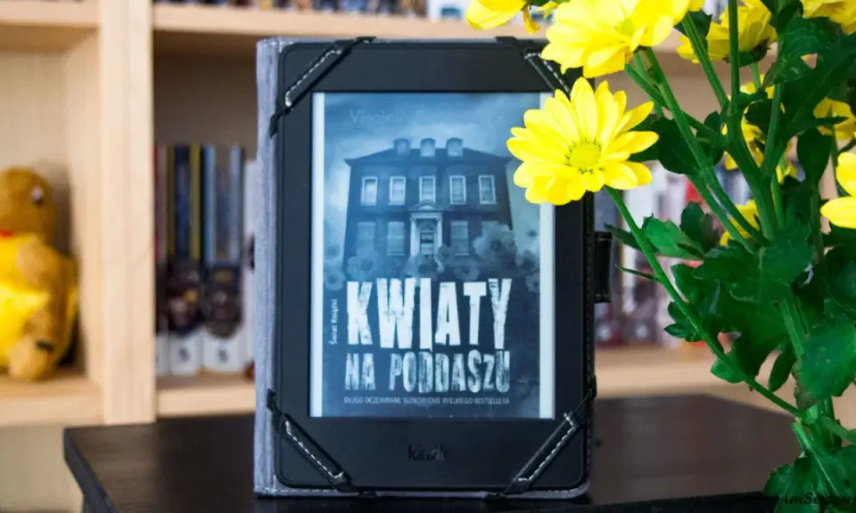 Elektroniczna książka z okładką "Kwiaty na poddaszu" obok bukietu żółtych chryzantem.
