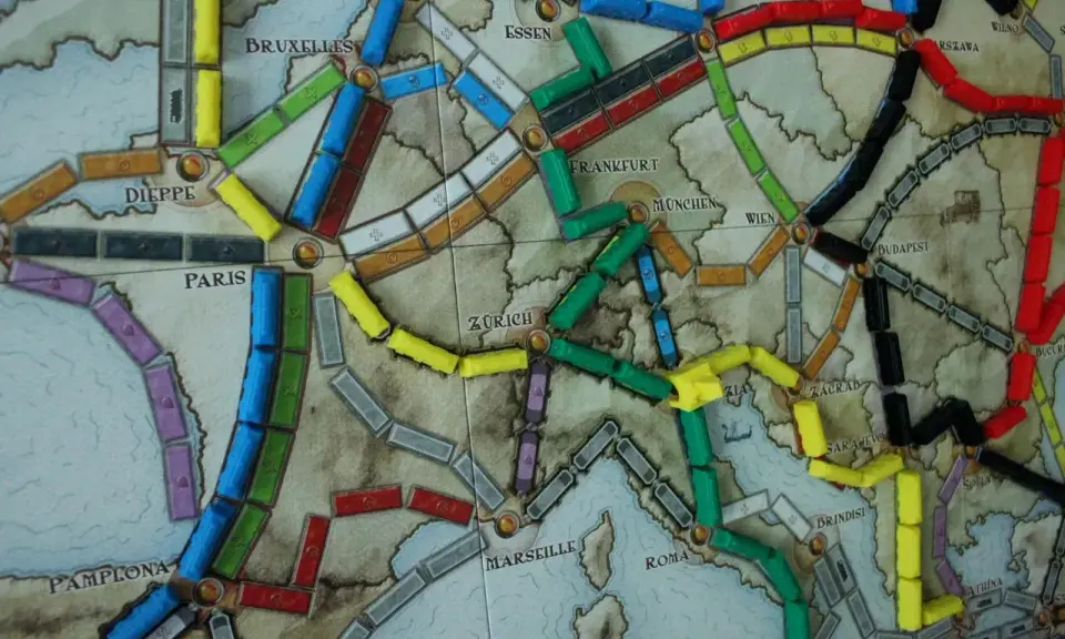Planszowa mapa Europy z kolorowymi wagonikami. Która trasa jest najlepsza, by wsiąść do pociągu i odkryć nowe miasta?