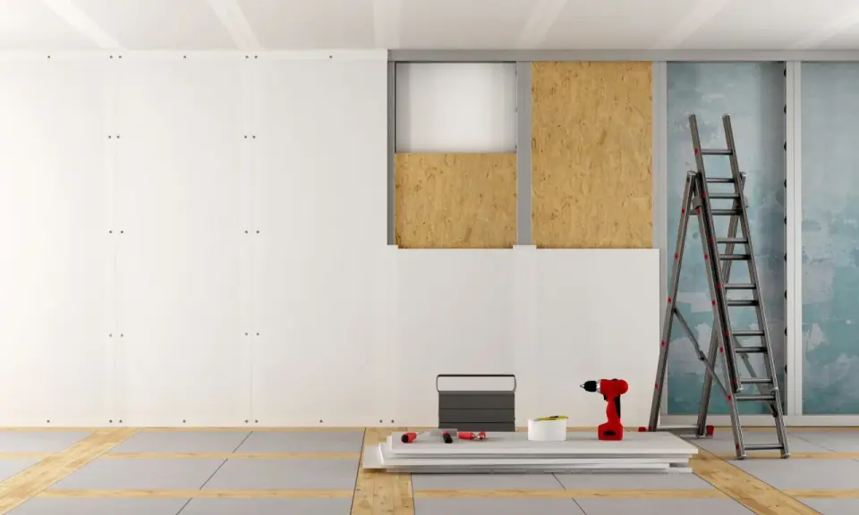 Chantier de pose de plaques de plâtre, avec échelle, perceuse et matériaux. Estimation du prix placo m2.