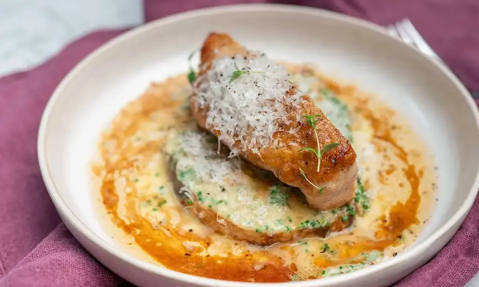 En elegant rätt med kött, grön puré och en krämig sås, toppad med riven ost och örter. Ett perfekt fine dining recept.