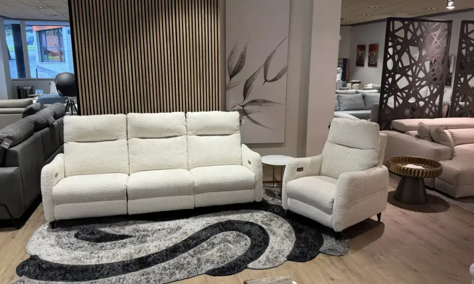 Sofá blanco de tres plazas y butaca a juego, perfectos para combinar sofá y butaca en tu salón. Alfombra moderna y cuadro decorativo.