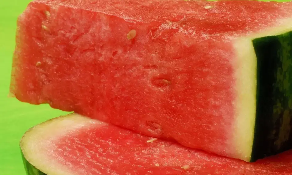 Saftige Wassermelonenstücke auf grünem Hintergrund. Perfekt für eine leichte Erfrischung, da Wassermelone kalorienarm ist.