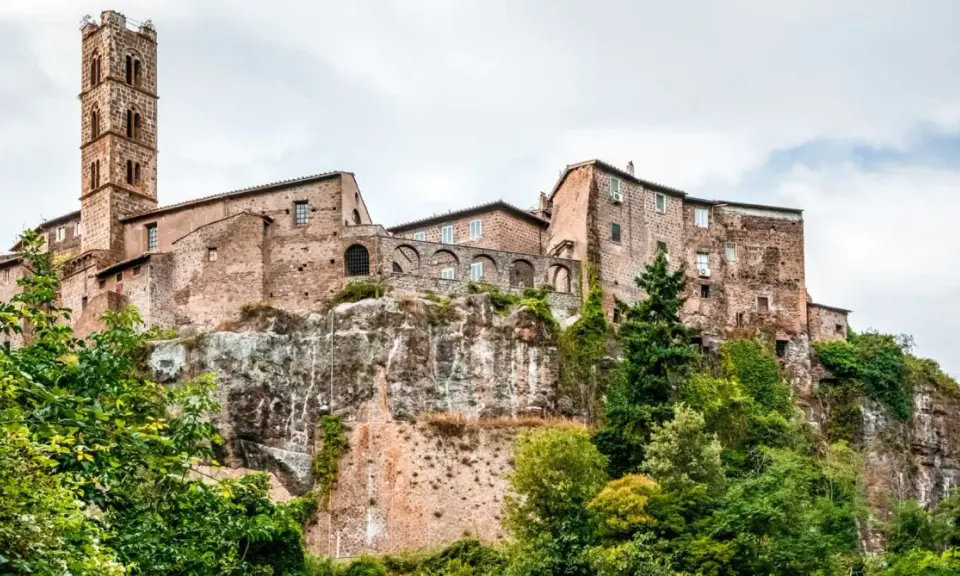 Un borgo medievale arroccato su una rupe, con un'alta torre campanaria. Un esempio dei borghi più belli del Lazio, immerso nel verde.