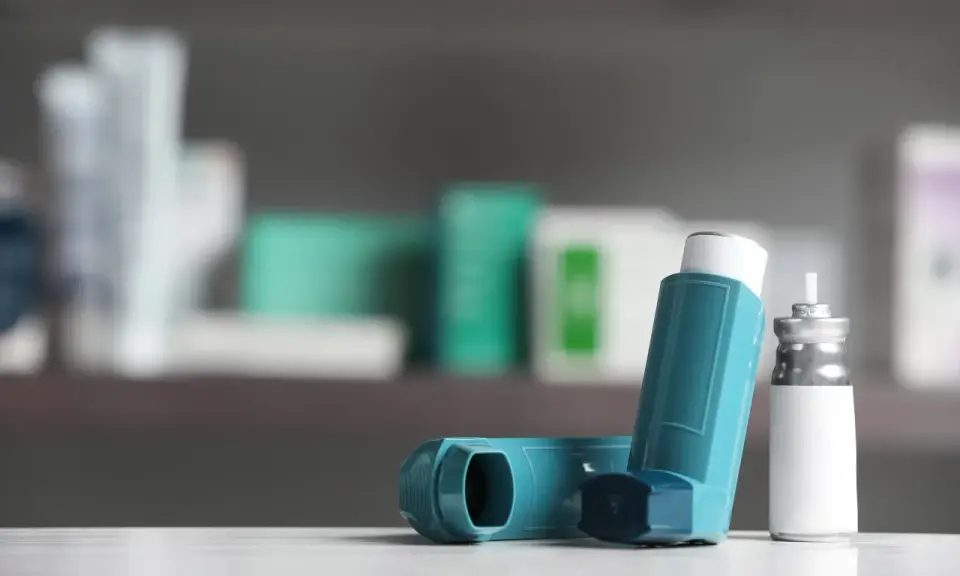 Zwei Inhalatoren, einer davon mit einem silbernen Behälter, liegen auf einer weißen Oberfläche. Sie sind wichtige Hilfsmittel bei der Behandlung von COPD, wo Cortison oft eine Rolle spielt.