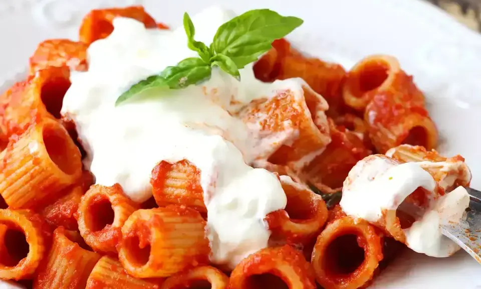 Rigatoni al sugo rosso con abbondante stracciatella cremosa e una fogliolina di basilico fresco.