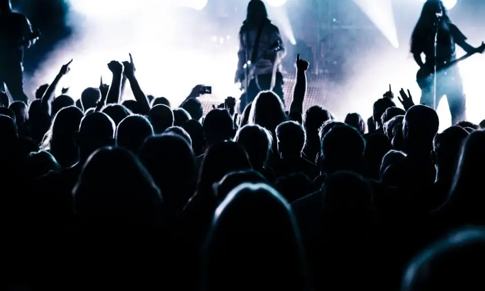 Tłum szaleje na koncercie, ręce w górze, światła sceny tworzą atmosferę legendy historii rocka.
