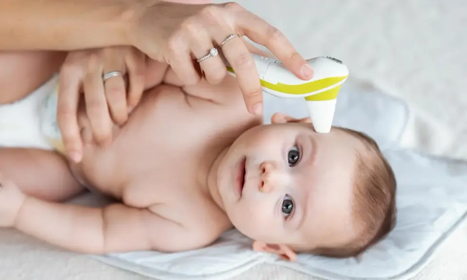Mama mierzy temperaturę niemowlaka termometrem bezdotykowym.