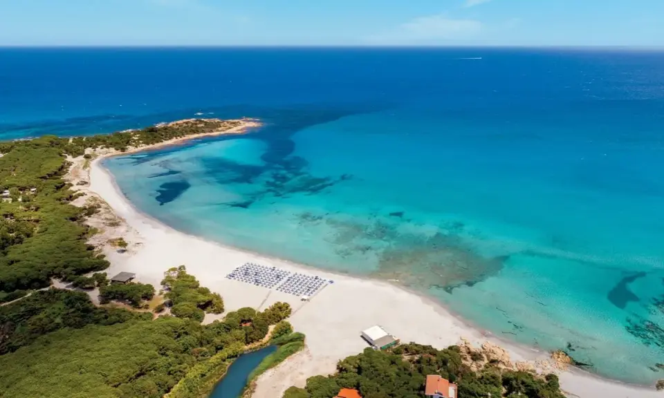 Spiaggia bianca e mare cristallino in Sardegna, ideale per villaggi per famiglie.