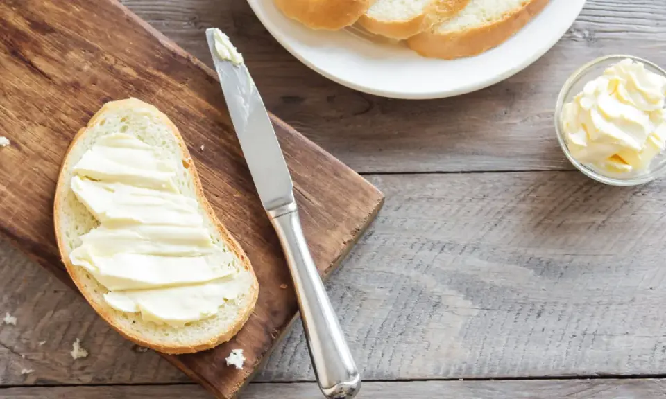 Brot mit Butter bestrichen, daneben eine Schale mit Butter und ein Messer. Ob Butter oder Margarine, beides enthält Cholesterin.