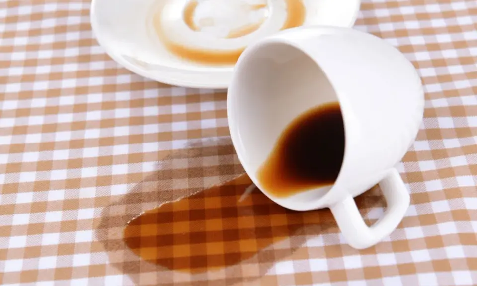Um Kaffeeflecken aus Tischdecke zu entfernen, braucht es Geduld. Eine umgekippte Tasse hinterließ einen braunen Fleck auf kariertem Stoff.