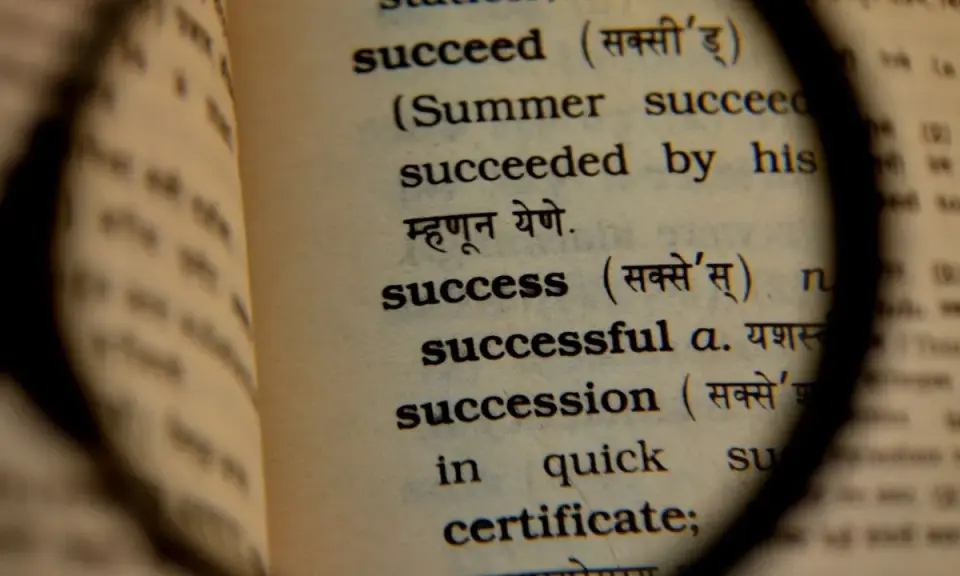 Słownik pod lupą ukazuje definicję słowa "success", czyli sukces. To droga do osiągnięcia celu.