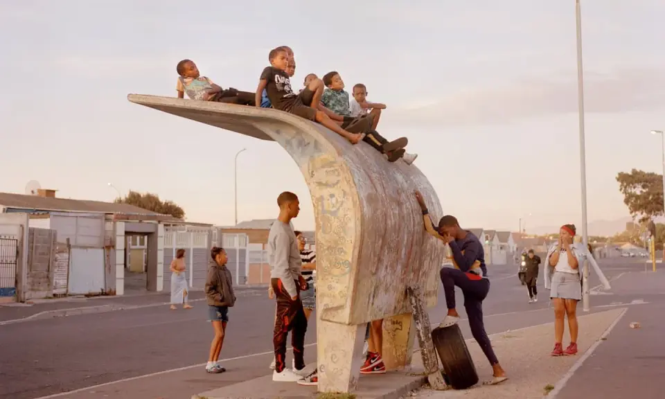 Kids gather on a unique bus stop structure, a scene that could be featured in a Belfast photo festival, capturing everyday life.