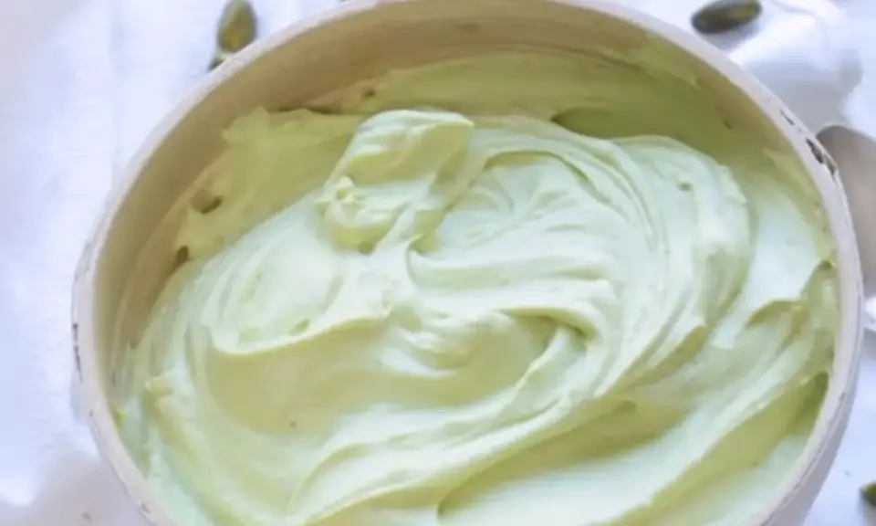 Un bol rempli de ganache pistache onctueuse, parsemé de pistaches entières. Une gourmandise verte et appétissante.