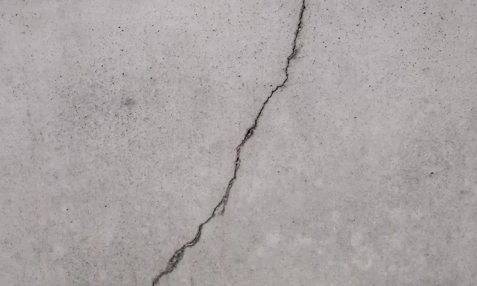 Ein Riss im Betonboden zeigt die Notwendigkeit, den Estrich reparieren zu lassen, um weitere Schäden zu vermeiden.