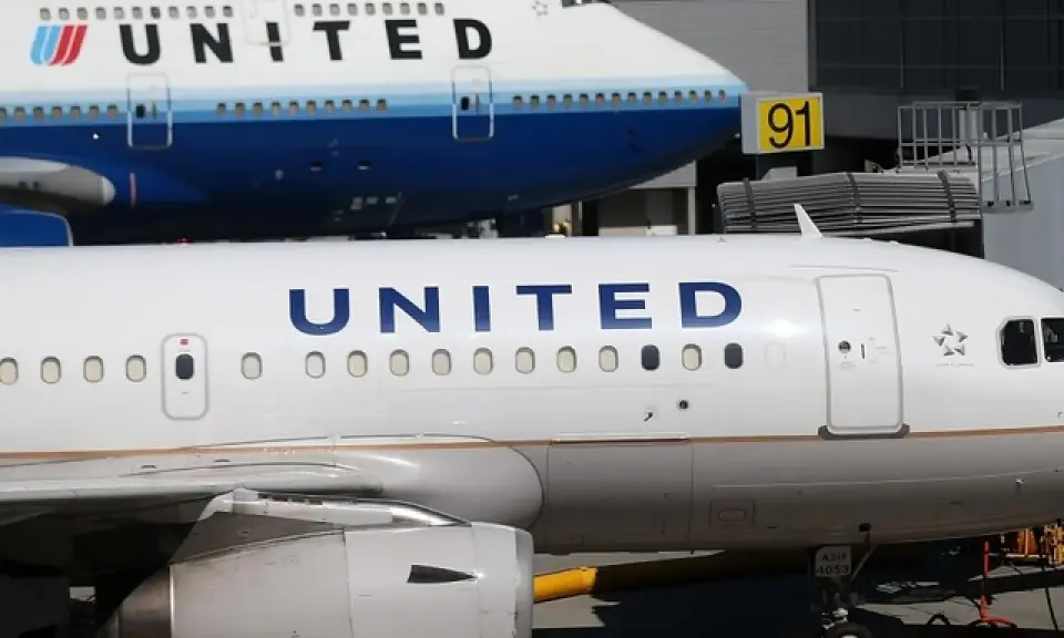 Dwa samoloty United Airlines na płycie lotniska. Jeden z nich to Boeing 747, drugi to mniejszy samolot. W tle widać budynek terminala.