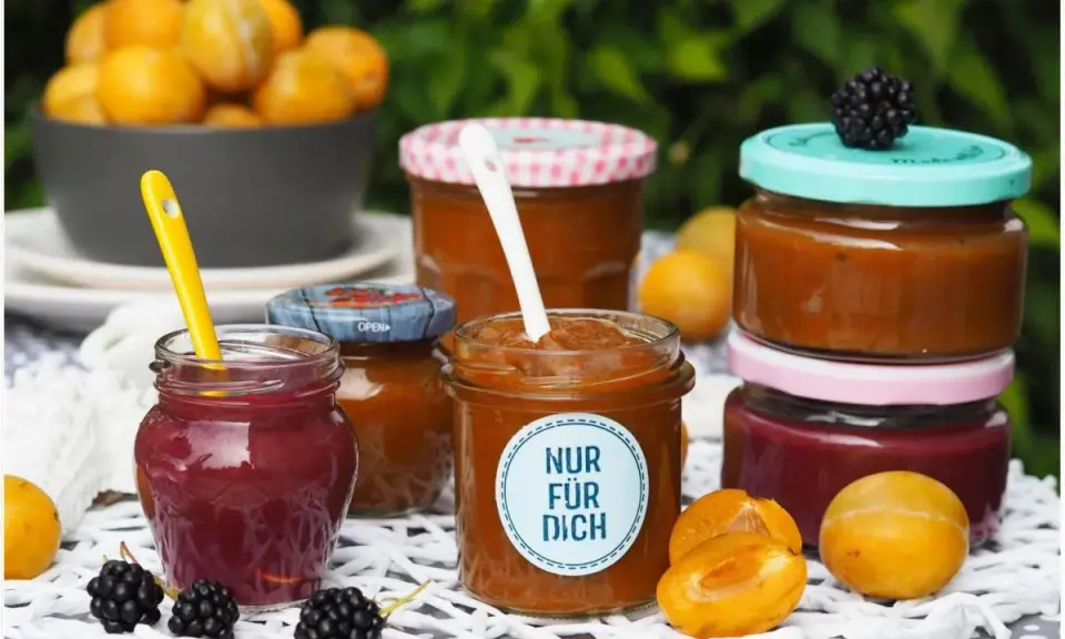 Marmelade ohne Gelierzucker haltbar machen: Mehrere Gläser mit selbstgemachter Marmelade, Früchten und Beeren.
