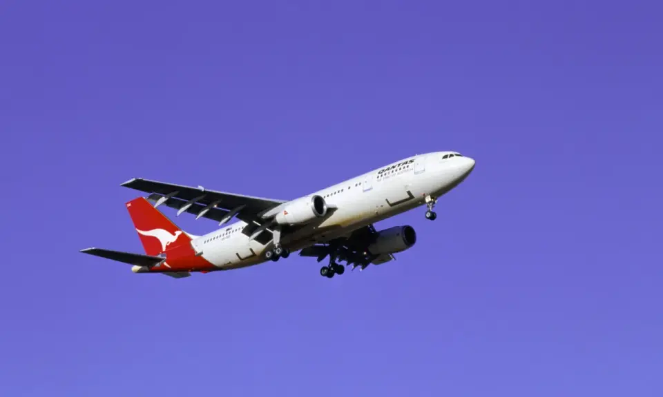 Samolot Qantas z charakterystycznym kangurem na ogonie, symbolizujący najbezpieczniejsze linie lotnicze, leci na tle błękitnego nieba.