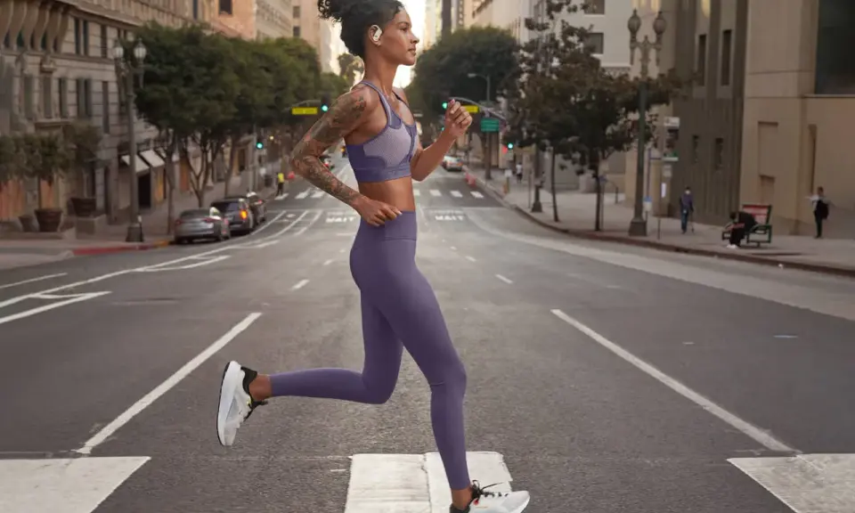 Donna in outfit viola, perfetto per come vestirsi in palestra, corre in strada.