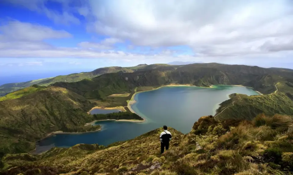 Ein Mann blickt auf eine atemberaubende Kraterlandschaft mit mehreren Seen. Die Frage, ob Madeira zu den Azoren gehört, wird hier durch die Schönheit der Natur beantwortet.