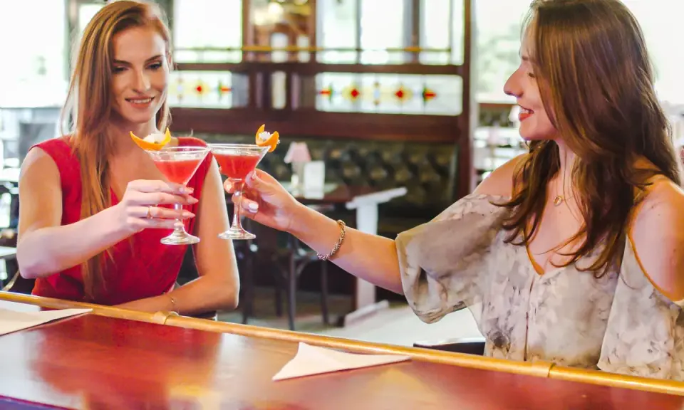 Dwie przyjaciółki wznoszą toast drinkami w barze. Idealny weekend z przyjaciółką!