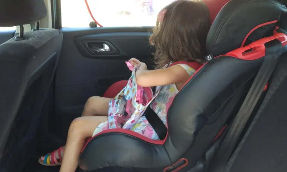 Niña en silla de coche, lista para el viaje. Aún no es el momento cuando puede ir un niño sin silla en el coche.