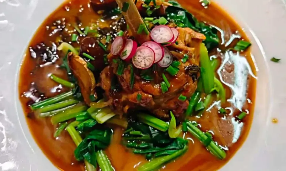 Un plat savoureux, un os de viande braisé dans une sauce riche, garni de radis et de légumes verts. Un aperçu des spécialités parisiennes.
