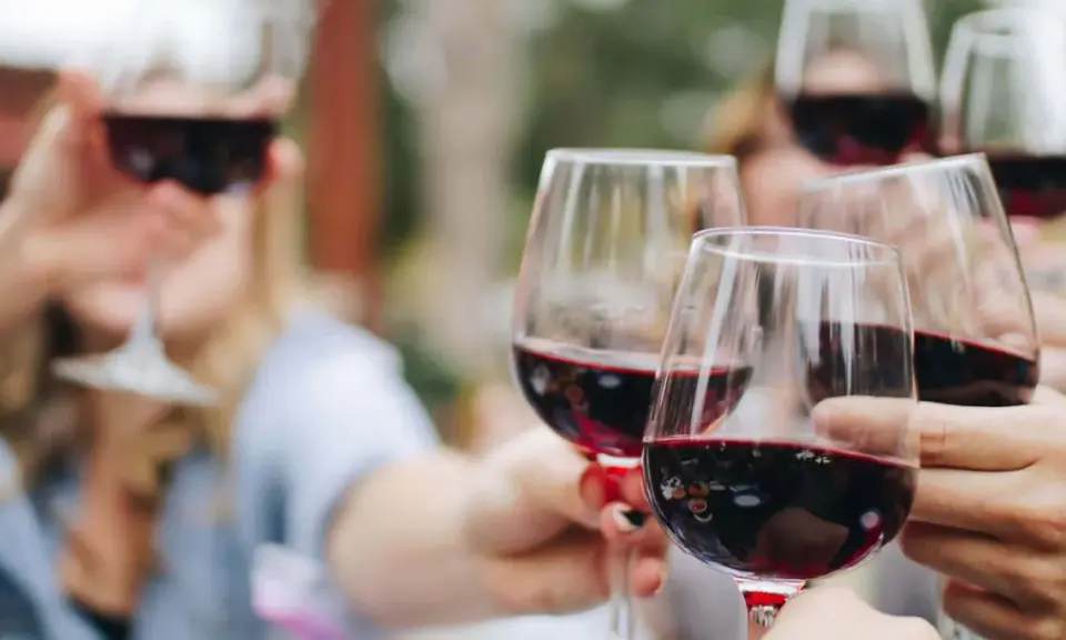 Des verres de vin rouge levés en toast. Pour 40 personnes, combien de bouteille de vin prévoir ? Environ 15 à 20 bouteilles.