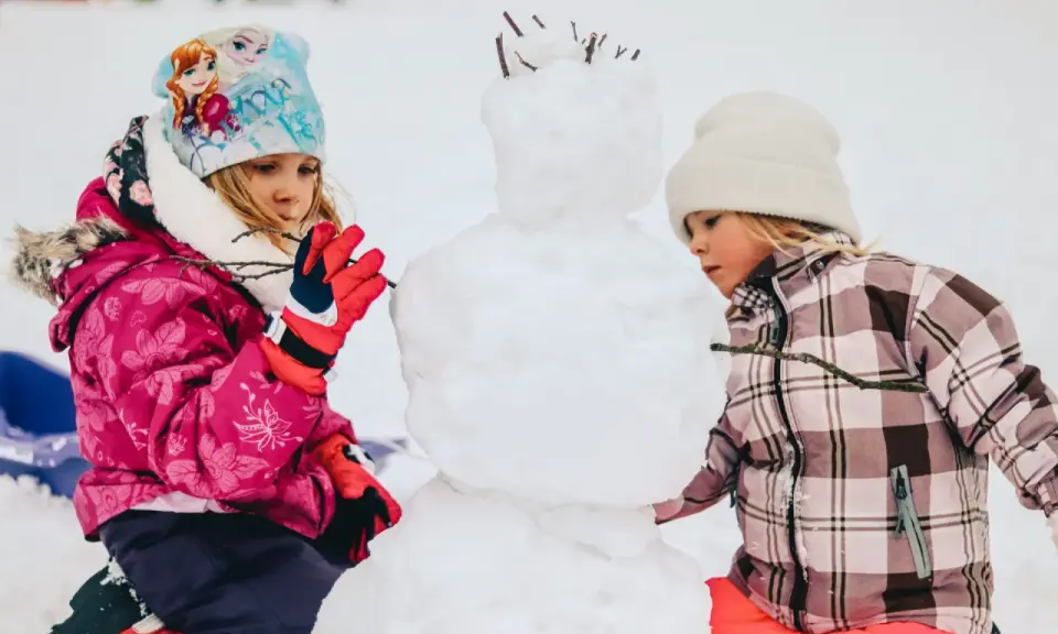 Bambini creano un pupazzo di neve in montagna, un vero natale in montagna con bambini che si divertono nella neve.