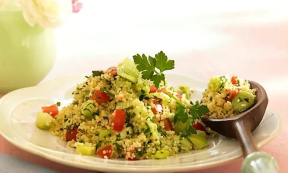 Frischer Couscous-Salat mit Tomaten, Gurken und Kräutern, garniert mit Petersilie. Ein Löffel voller Genuss.