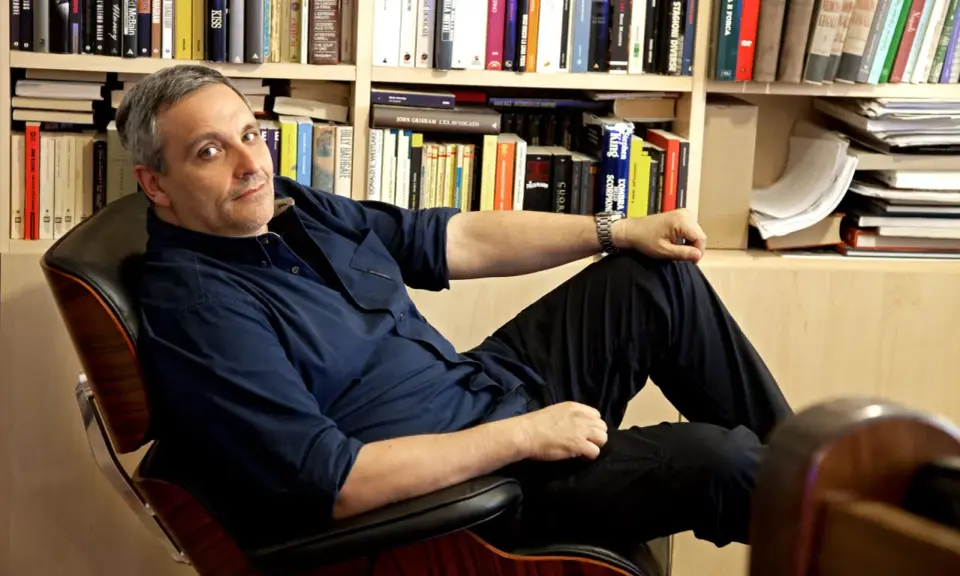 L'autore, circondato da libri, si rilassa su una poltrona. Tra i titoli, si intravede un riferimento a de Giovanni ultimo libro.