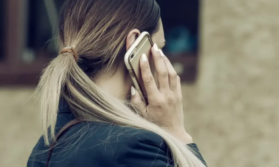Kobieta rozmawia przez telefon, być może dowiadując się o **siłę wyższą kodeks pracy**.