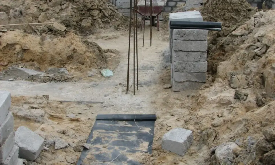 Budowa fundamentu z bloczków betonowych, zbrojenie i wózek widłowy w tle.
