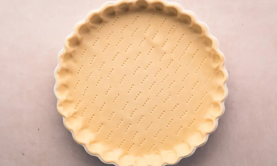 Pâte brisée salée prête à être garnie. Les petits trous préparent la base pour une cuisson parfaite.