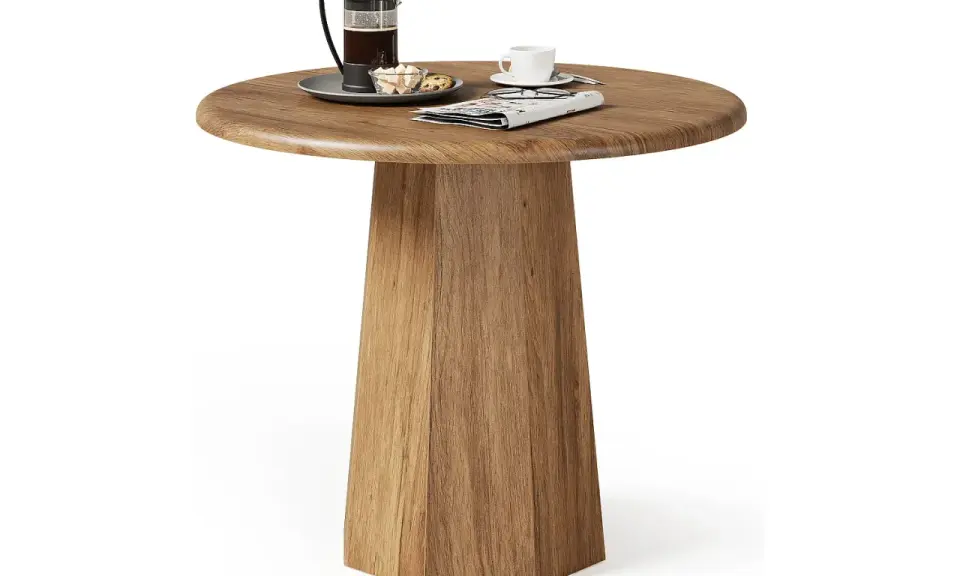 Ett runt, träfärgat litet slagbord med en kaffepress, en kopp och en tidning.
