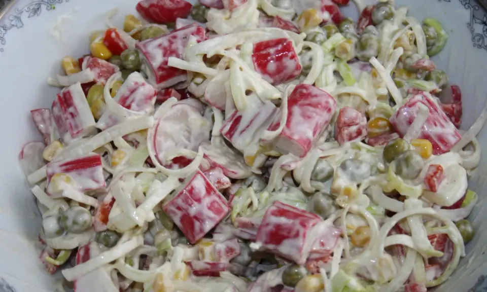 Pyszna sałatka z paluszkami surimi, groszkiem, kukurydzą i porem, polana kremowym sosem.