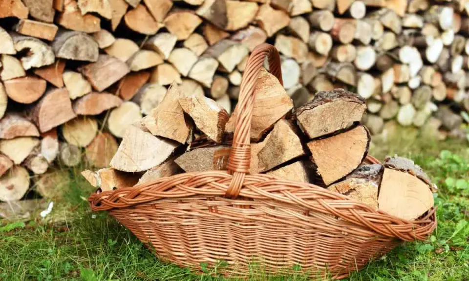 Panier en osier rempli de bois de chauffage, prêt à être utilisé pour protéger le bois de l'humidité.