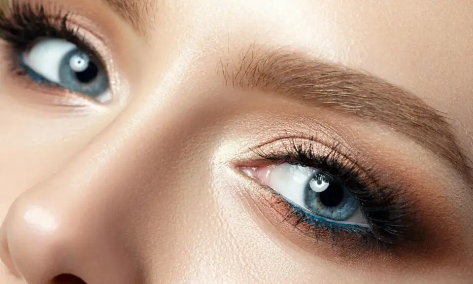 Nahaufnahme eines blauen Auges mit braunem Lidschatten und blauer Eyeliner-Linie. Perfekt für die Frage: welche haarfarbe bei blauen augen.