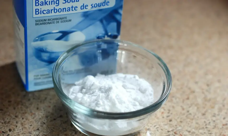 Un bol de bicarbonate de soude à côté de sa boîte. Un ingrédient polyvalent, utile pour le nettoyage et la cuisine, et même pour des expériences scientifiques impliquant de l'aluminium.