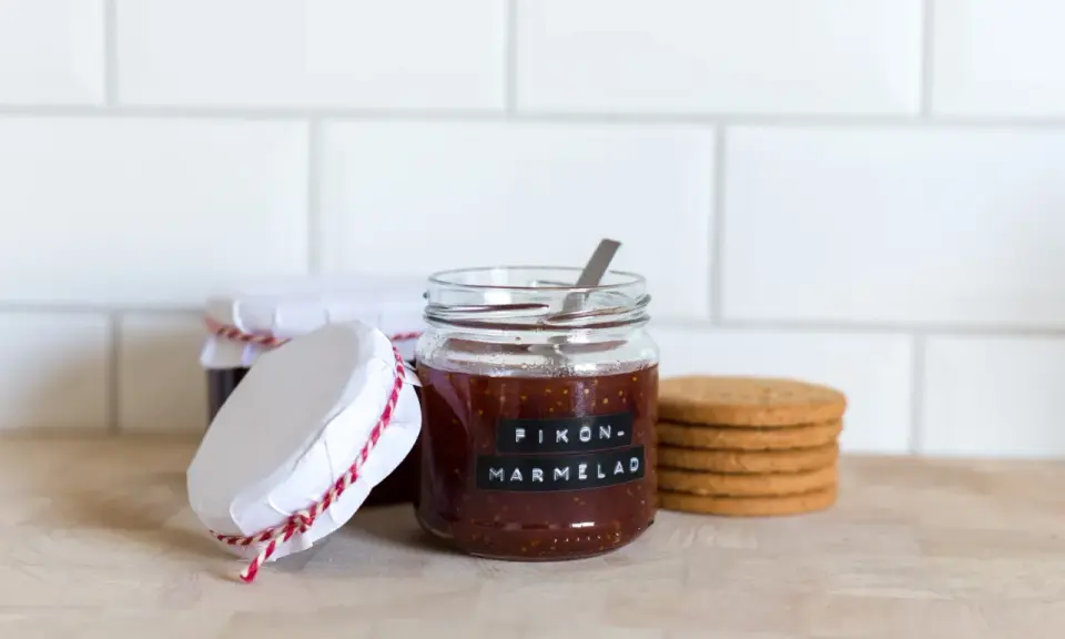 Burkar med hemlagad fikonmarmelad, perfekt för ett enkelt fikonmarmelad recept. En sked sticker upp ur den främsta burken.